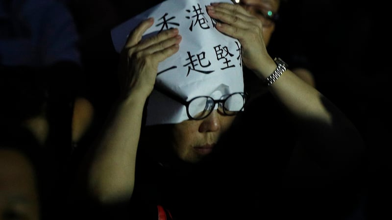 一名香港民众在头上放着“香港 一起坚持”的标语。（美联社）