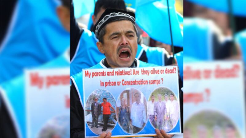 资料图片:2018年11月6日,一名男子在瑞士日内瓦联合国办事处前参加抗议中国新疆政策。他所举的海报上写着:我的父母和亲人们!他们活着还是死了?他们在监狱里还是在再教育营中?(My parents and relatives!Are they alive or dead?in prison or Concentration camps?)。(图/路透社)