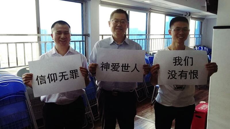 资料图片:王怡牧师(中)和信徒手持标语:“信仰无罪 神爱世人 我们没有恨”。(图源:秋雨之福大抓捕脸书)