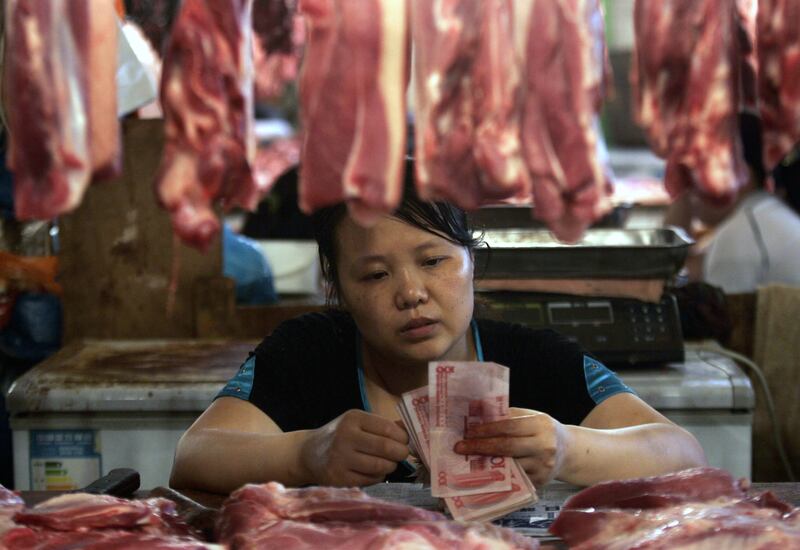 资料照：重庆市的一名猪肉摊贩在市场上清点人民币。