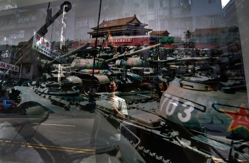 资料图片：一名男子看着一张照片，1989 年 6 月 4 日在北京天安门广场拍摄的。 （美联社）