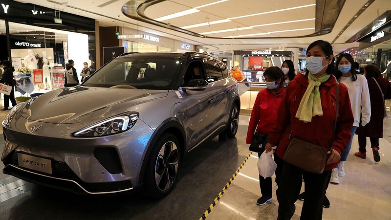 今年首季经济面对疫情考验及外部环境不确定。图为,2021年4月16日,人们走过在中国北京新开业的购物中心展示的电动汽车。(路透社)