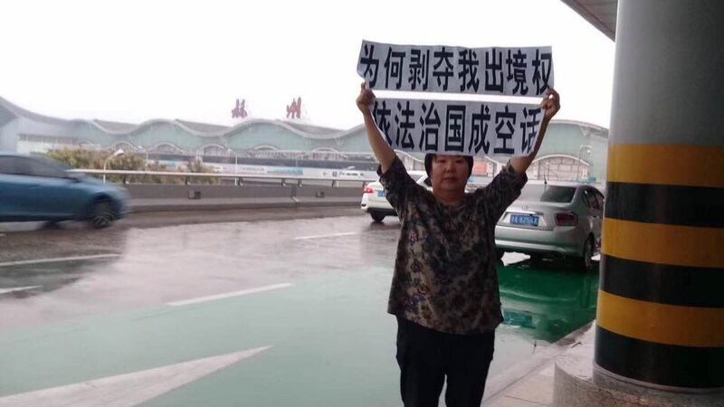 资料图片:陈建芳举牌抗议当局限制其出境。(推特图片)