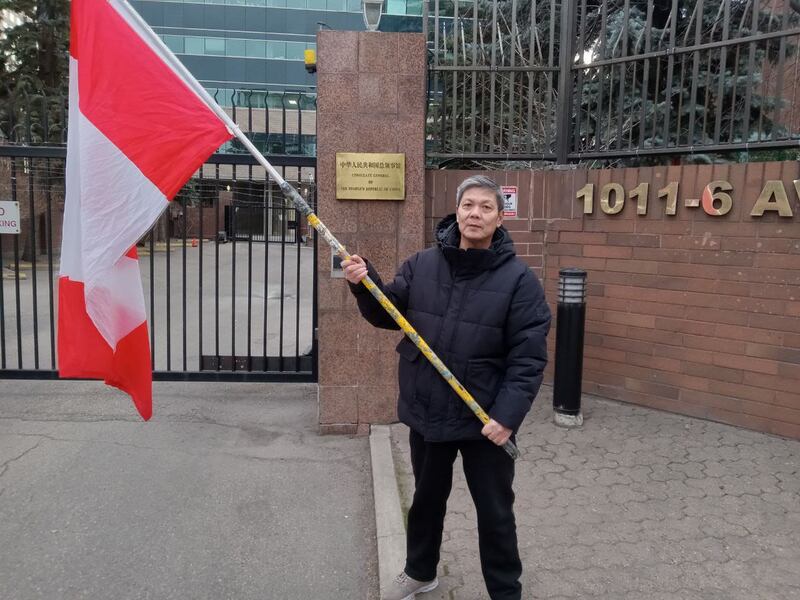 陈思明举着加拿大国旗在中国驻卡尔加里的领事馆前抗议,他称中国当局用尽多种方法,就是要让他们这些流亡海外的异议人士感到害怕不安。 (陈思明独家提供)