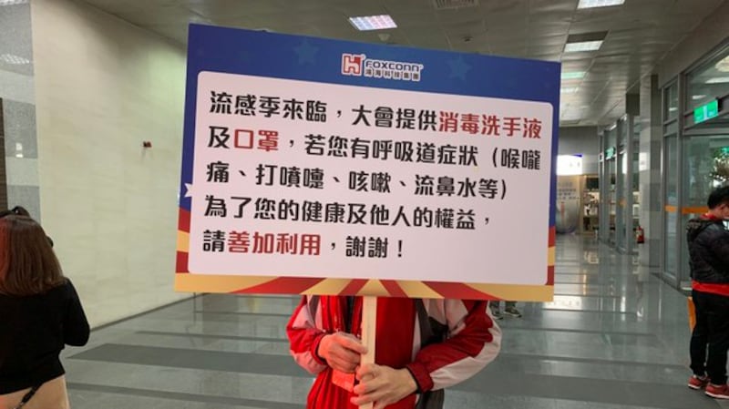 鸿海尾牙工作人员举牌提醒员工戴口罩。(记者 黄春梅摄)