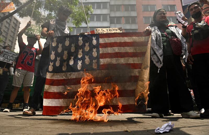 Filipino activists burn a mock American flag in front of the United States Embassy in Manila, as U.S. Defense Secretary Pete Hegseth visited the Philippine capital, March 28, 2025.