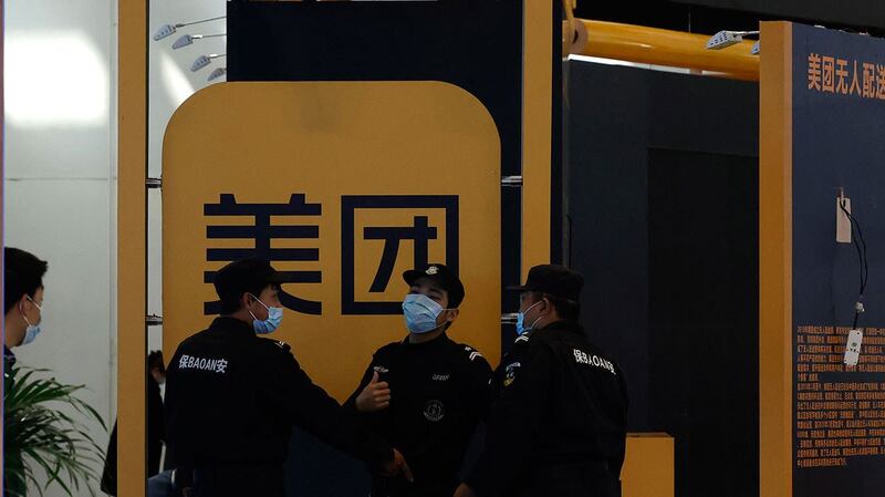 2021 年 4 月 30 日，在北京举行的互联网技术博览会上，保安人员在美团标志附近。 （美联社）