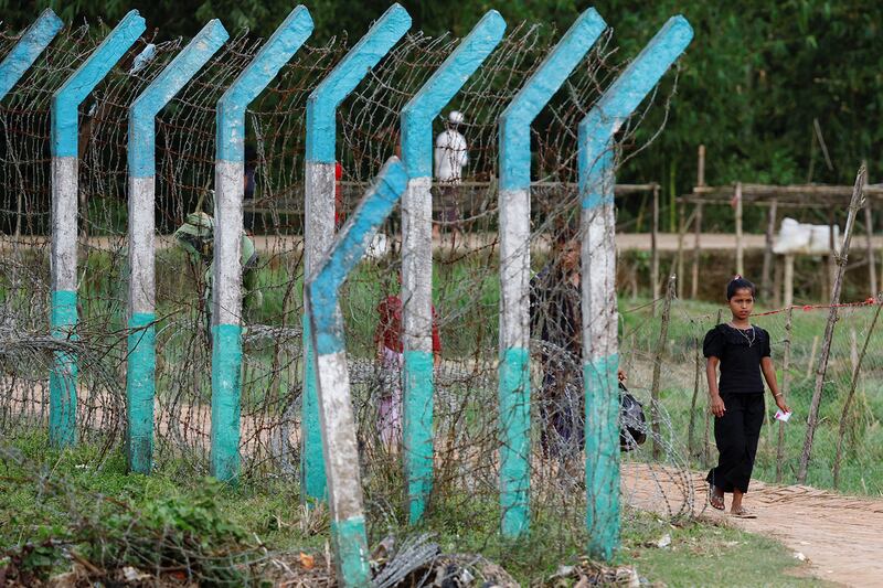 A Rohingya refugee walks past a camp border fence in Cox's Bazar, Bangladesh, Sept. 28, 2024.