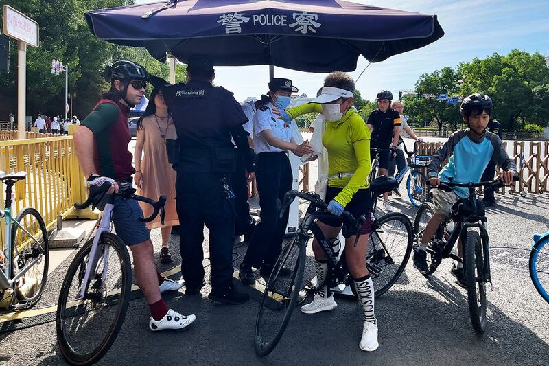 2023年6月4日，一名骑车的外国人（左一）在北京东长安街的安检点等待身份检查。（美联社）