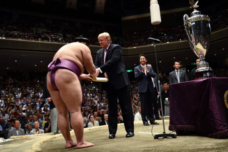 特朗普穿皮鞋进“土俵”颁发奖杯,打破不得穿鞋进入“土俵”的相扑传统。安倍如此安排被视为将有大改革。“土俵”是相扑力士竞技的圆圈,非常神圣。(AFP)
