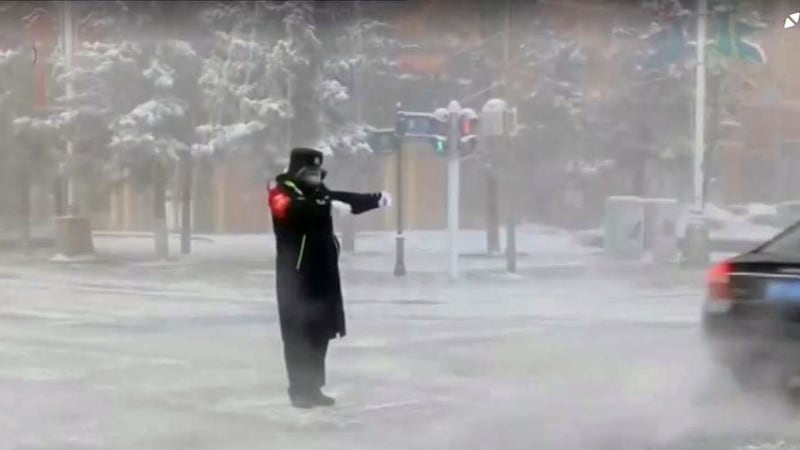 2023年1月22日,黑龙江省漠河市下雪公路上的交通警察在指挥交通。(路透社视频截图)