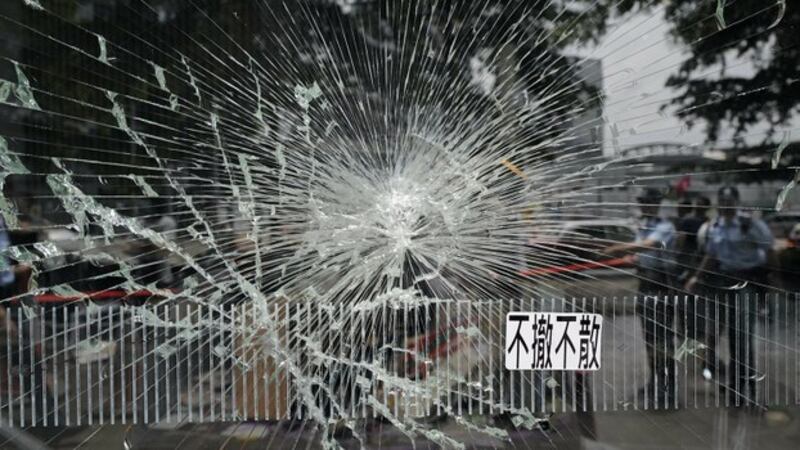 警方在香港立法会大楼破损的一面玻璃窗外执勤（美联社）