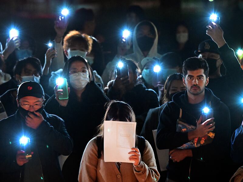 A woman holds a blank sheet of paper as demonstrators protest the deaths caused by an apartment complex fire in Urumqi, Xinjiang, China, at the Langson Library on the campus of the University of California, Irvine, in Irvine, California, on November 29, 2022.