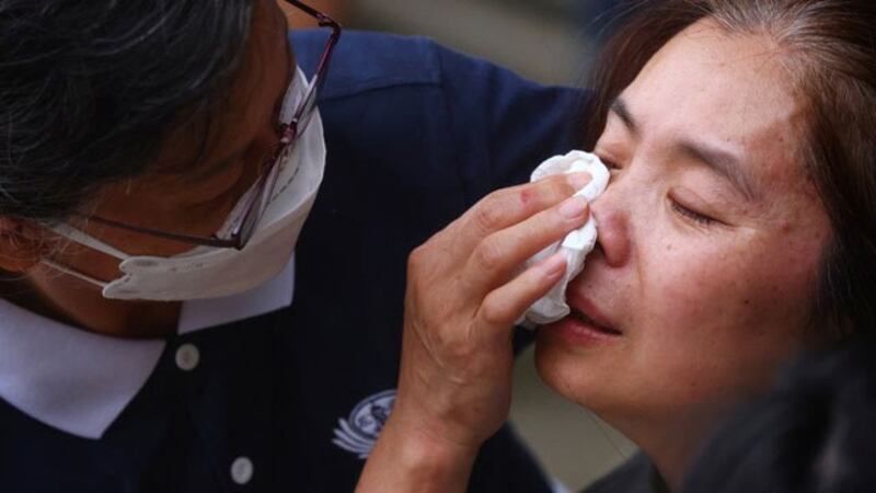 现场志工为家属抹去眼泪。(图源:路透)